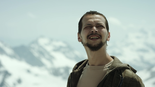 Young Bearded Man at Mountain Vertex with Scenic View Squint Eyes and Talking