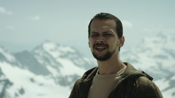 Young Bearded Man at Mountain Summit with Scenic View Squint Eyes and Talking