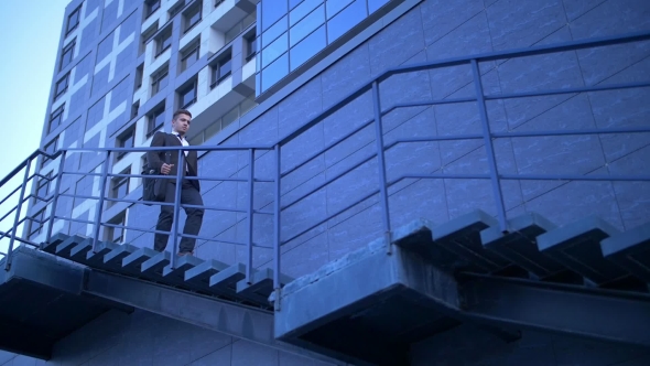 Young Stylish Businessman Walking Up the Stairs Towards Office Building