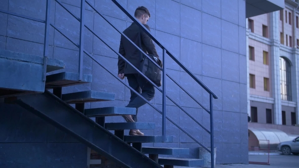Young Stylish Businessman Walking Up the Stairs Towards Office Building