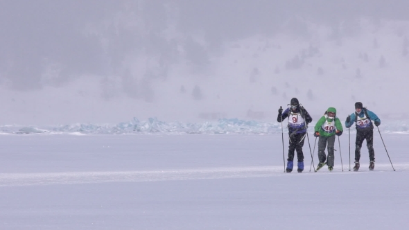 Group of Three Skiers and Cyclists Racing on Skis on the Ice.