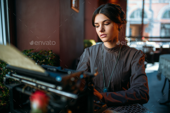 Serious lady prints on ancient typewriter - Stock Photo - Images