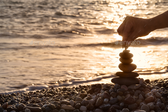Female hand setting pebble to the top of pyramid - Stock Photo - Images