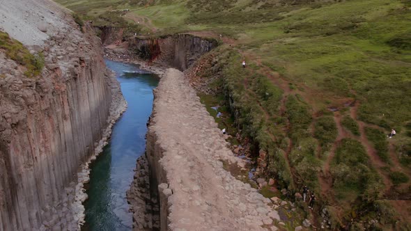 Studlagil Canyon and View of Grassy Horizon and Basalt Pillars with River alt