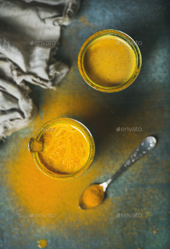 Golden milk with turmeric powder in glasses over dark background - Stock Photo - Images