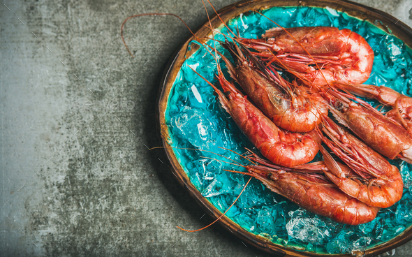 Raw uncooked red shrimps on chipped ice, grey concrete background - Stock Photo - Images