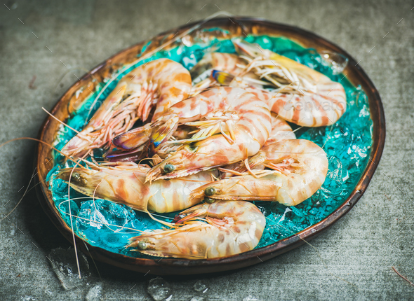 Raw uncooked tiger prawns on chipped ice, concrete background - Stock Photo - Images