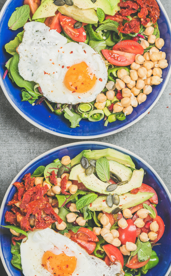 Close-up of breakfast with fried egg, chickpea, vegetables, seeds, greens - Stock Photo - Images