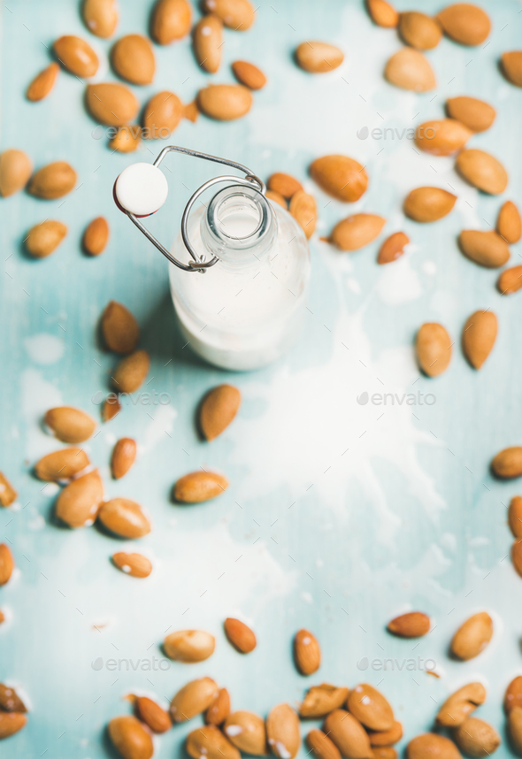 Almond milk in bottle and fresh nuts over blue background - Stock Photo - Images