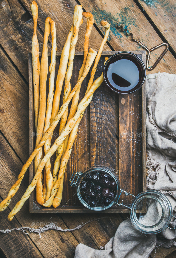 Grissini bread sticks, black olives, red wine in wooden tray - Stock Photo - Images