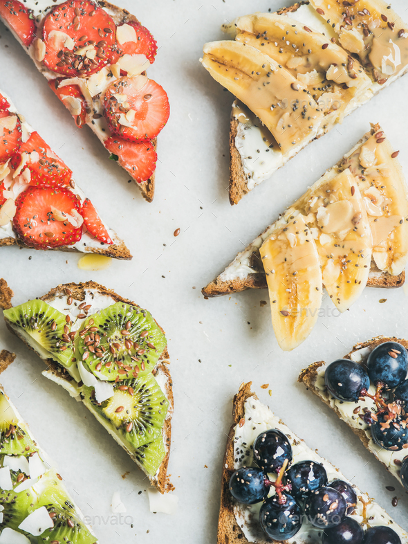 Healthy breakfast toasts with cream-cheese, fruit, nuts and seeds - Stock Photo - Images