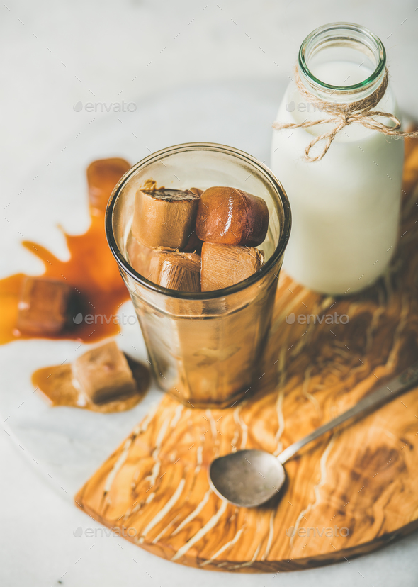 Glass with frozen coffee ice cubes and milk on board - Stock Photo - Images
