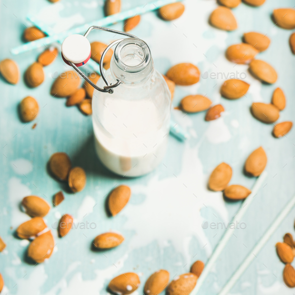 Dairy alternative almond milk in glass bottle over blue background - Stock Photo - Images