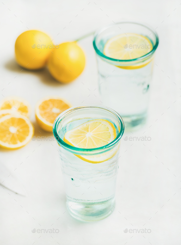 Detox lemon water in glasses served with fresh lemons - Stock Photo - Images