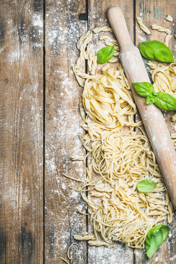 Various homemade fresh uncooked Italian pasta with flour, basil - Stock Photo - Images