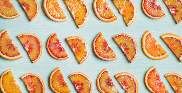 Fresh juicy blood orange slices over blue background, wide format - Stock Photo - Images
