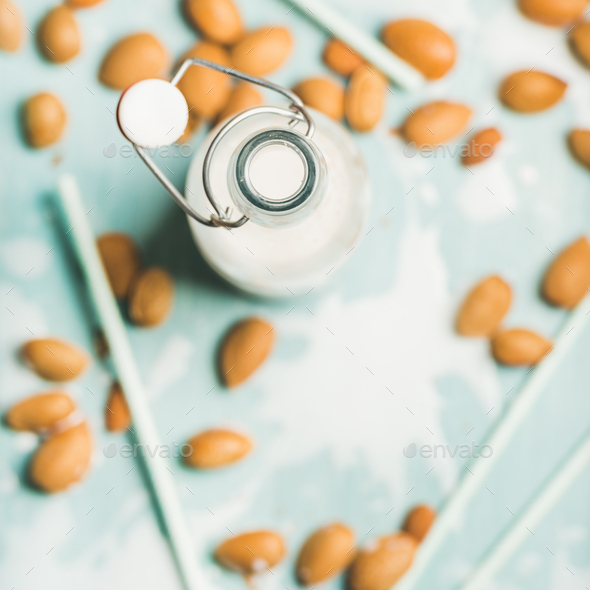 Almond milk in glass bottle over blue background, square crop - Stock Photo - Images