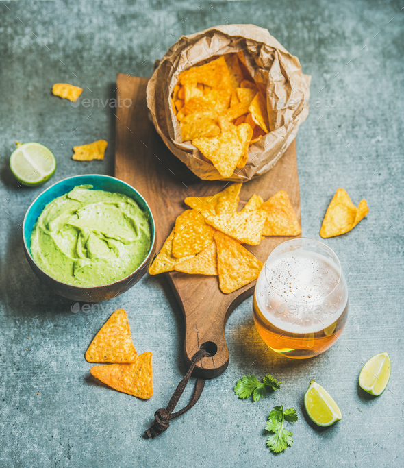 Mexican corn chips, fresh guacamole sauce and beer, concrete background - Stock Photo - Images