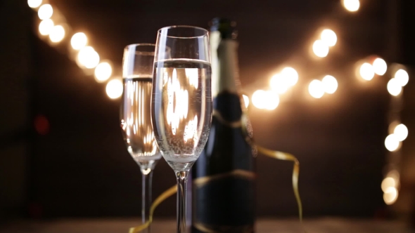 Two Flutes with Sparkling Wine Over Holiday Bokeh Blinking Background