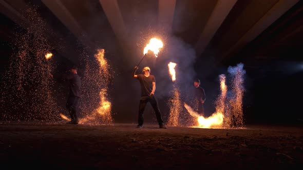 Fire show. Two men spin fire sparks. The third man exhales a huge flame alt