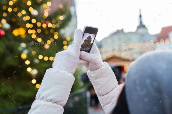 hands with smartphone photographing christmas tree
