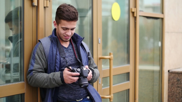 Young Guy Looks at the Digital Camera While in the City