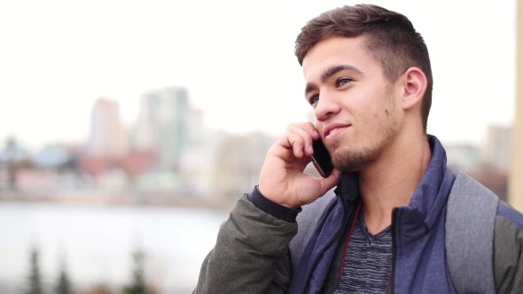 Young Stylish Man Talks on the Phone and Smiles in the City