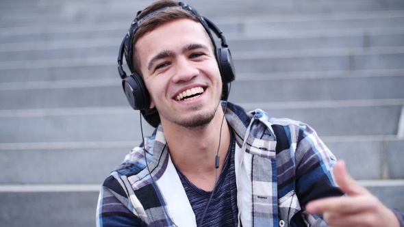 Young Trendy Man Listen To Music on Smartphone Sitting on the Steps Outdoor