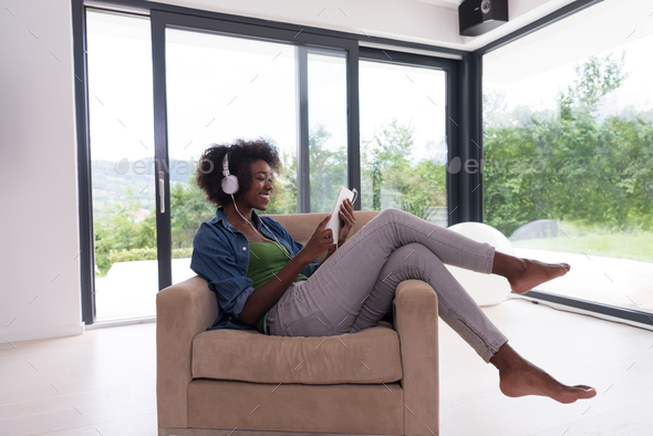 African american woman at home in chair with tablet and head pho - Stock Photo - Images