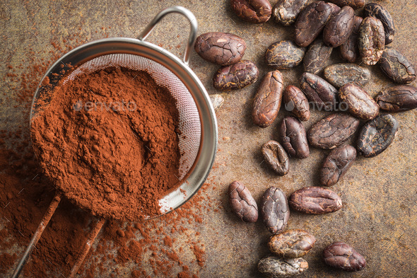 Dark cocoa powder in a sieve and cocoa beans.