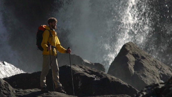 A Male Hiker Watches a Big Waterfall in .