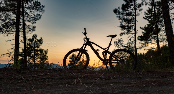 Mountain bike sunset silhouette on forest trail, inspiring lands