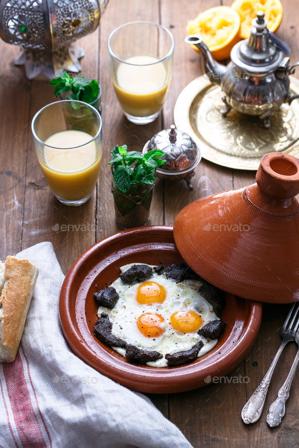 Sunnyside Eggs cooked in a Tajine dish with beef, Moroccan breakfast with juice and mint tea