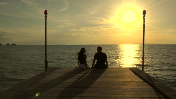 Romantic Couple on the Beach at Colorful Sunset on Background