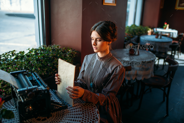 Happy young woman sits by the table in cafe - Stock Photo - Images