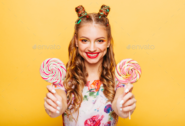 Smiling lady holding two huge colorful lollypops - Stock Photo - Images