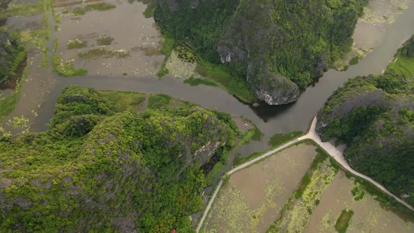 Aerial Shot of Beautiful Limestone Mountains with Passes Carved By a River in Ninh Binh Region a alt