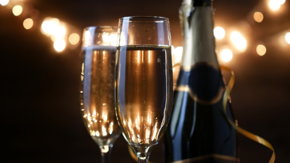 Two Flutes with Sparkling Wine over Holiday Bokeh Blinking Background