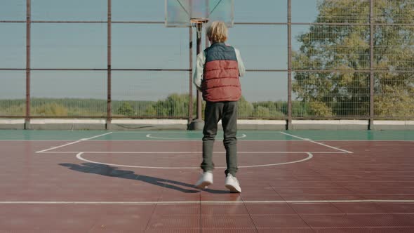 Boy Practicing on a Court Throwing a Basketball Ball in the Park