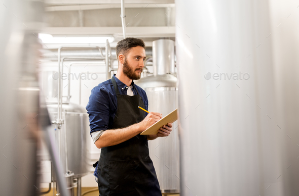 man with clipboard at craft brewery or beer plant - Stock Photo - Images