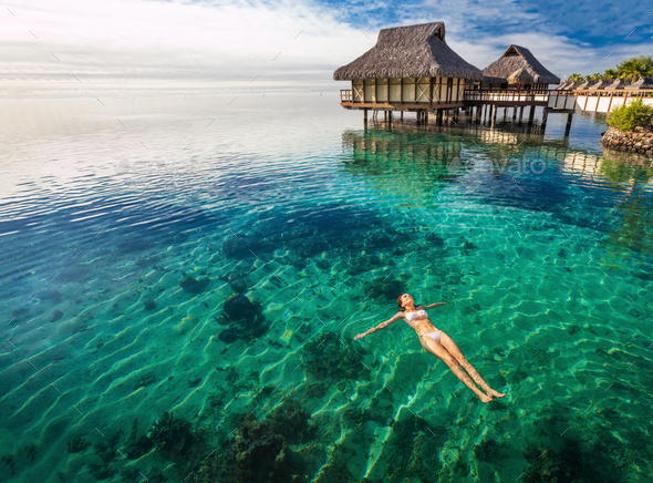 Woman in white bikini swimming in coral lagoon, Moorea, Tahiti