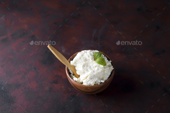 Fresh cottage cheese in a wooden bowl and spoon on - Stock Photo - Images
