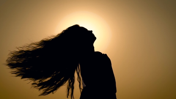 Woman Shaking with Hair on Background of Sunset Light on Sky alt