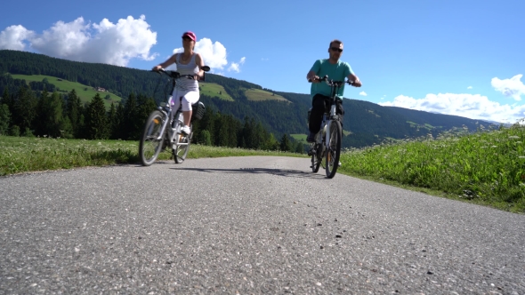 Couple Woman and Man on Electric Eco Bike Cycling Italy Dolomites Alps alt