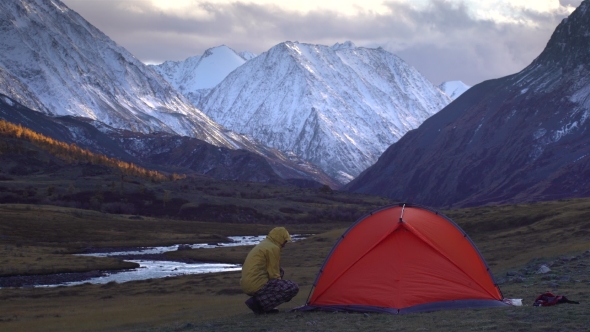 The Man Is Setting Up the Tent on the Background of Mountain Landscape.