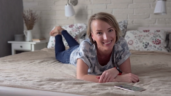 Woman Lying on Bed and Smiling
