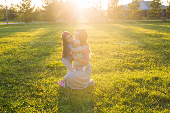 Mother with two little children hugging outdoors. Happy family concept - Stock Photo - Images