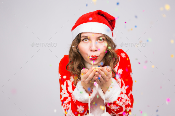 girl in Santa's costume welcoming the new year 2018 blowing confetti to camera