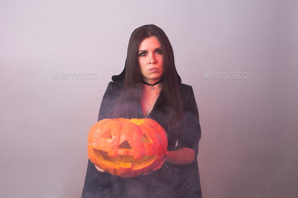 Halloween witch holding a orange pumpkin Jack o Lantern with smoke