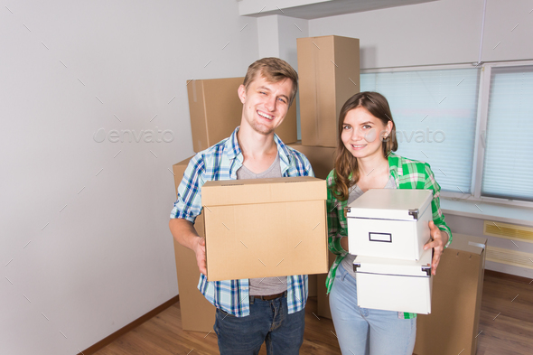home, people, moving and real estate concept - happy couple with cardboard boxes at new home
